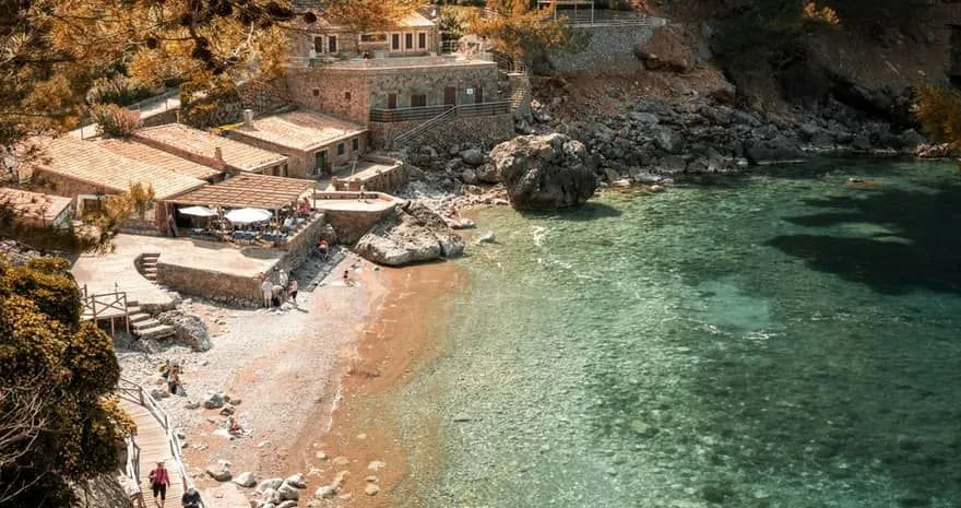 Cala de Deià mit kristallklarem Wasser und Felswänden auf Mallorca