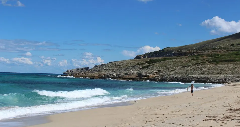 Badegäste genießen das türkisfarbene Wasser der Cala Mesquida im Osten Mallorcas